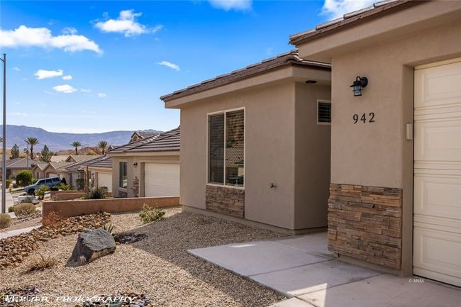 View of home's exterior with stucco siding, stone siding, an attached garage, a mountain view, and a tile roof | Image 4