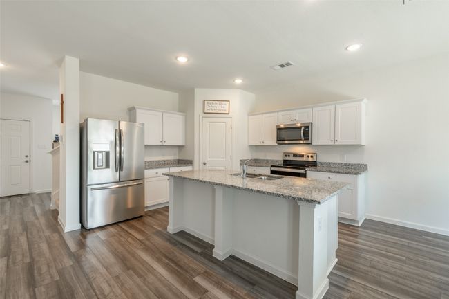 Kitchen with stainless steel appliances, a sink, dark wood-style floors, a center island with sink, and white cabinetry | Image 7
