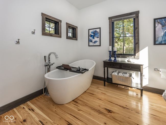 bathroom featuring a freestanding tub, baseboards, and wood finished floors | Image 22