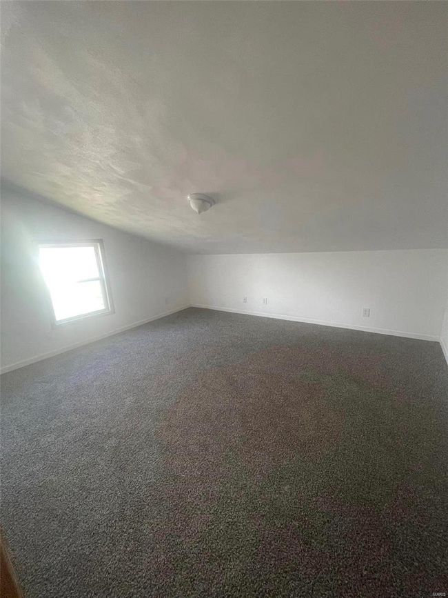 Empty room featuring baseboards, dark colored carpet, and lofted ceiling | Image 15