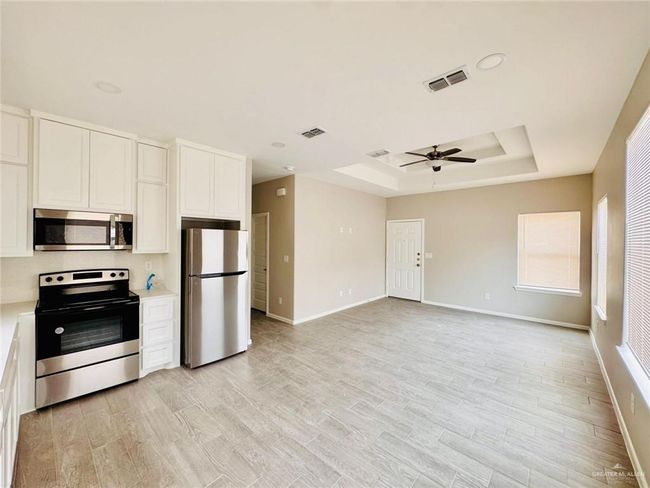 Kitchen featuring appliances with stainless steel finishes, a raised ceiling, ceiling fan, light countertops, and white cabinetry | Image 15