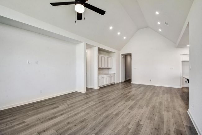 Unfurnished living room with a ceiling fan, high vaulted ceiling, recessed lighting, and wood finished floors | Image 11