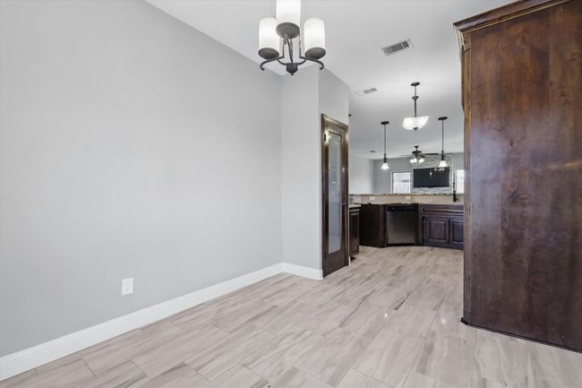 Kitchen featuring dishwasher, dark brown cabinetry, a chandelier, baseboards, and decorative light fixtures | Image 11