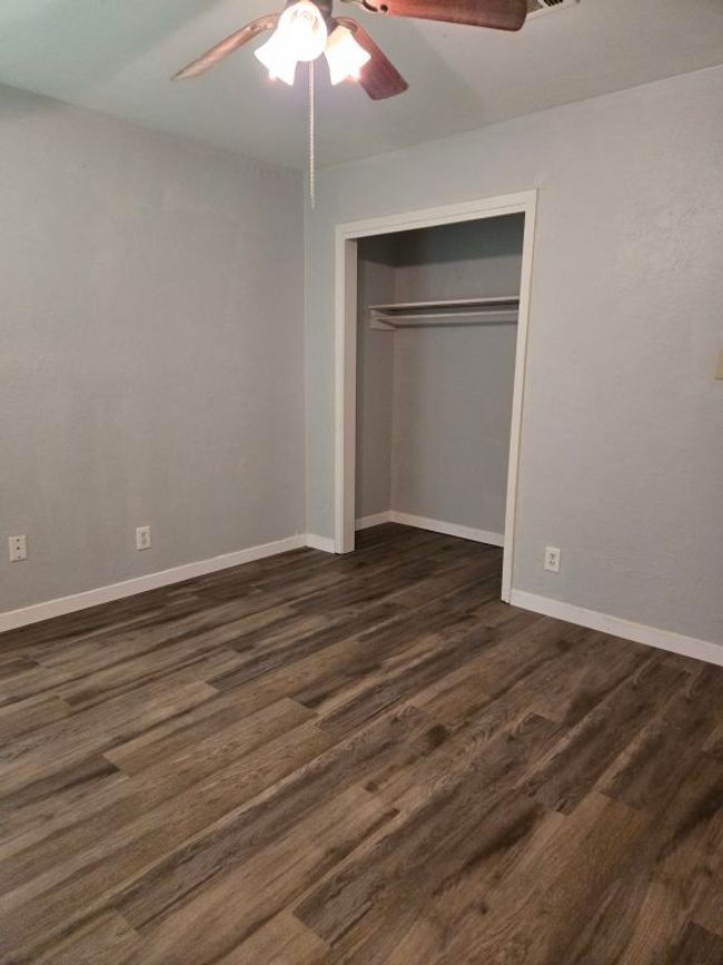 Unfurnished bedroom featuring dark wood-style floors, a closet, and a ceiling fan | Image 25