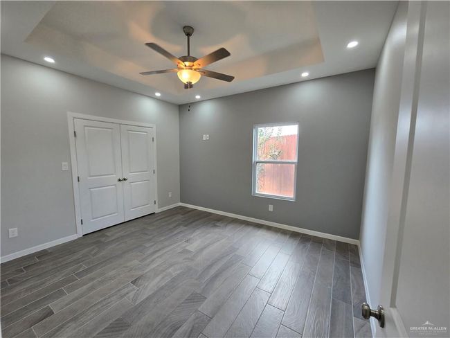 Unfurnished bedroom featuring dark wood-type flooring, baseboards, recessed lighting, and a ceiling fan | Image 17