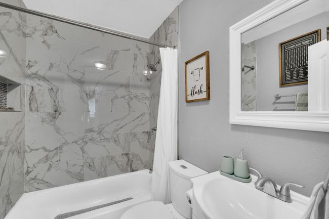 Full bathroom featuring shower / bath combination with curtain, toilet, and a sink | Image 25