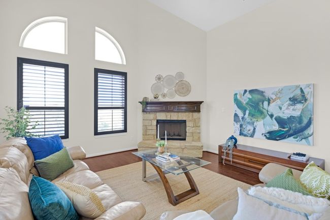 Living area featuring a stone fireplace, wood finished floors, baseboards, and high vaulted ceiling | Image 9