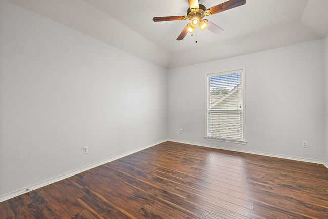 Upstairs guest room with dark wood-style floors, baseboards, a ceiling fan, and vaulted ceiling | Image 26