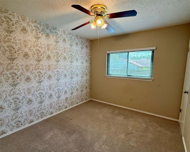 Unfurnished room featuring ceiling fan, a textured ceiling, carpet floors, wallpapered walls, and baseboards | Image 11
