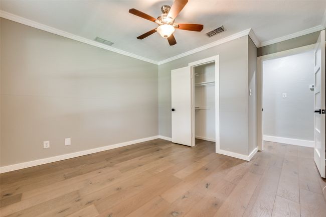 Unfurnished bedroom with crown molding, light wood-style flooring, a closet, and a ceiling fan | Image 22