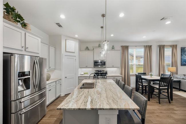 Open to the dining and living areas, this kitchen offers effortless flow for entertaining and daily living alike, with ample cabinetry and a large center island ideal for casual meals. | Image 7