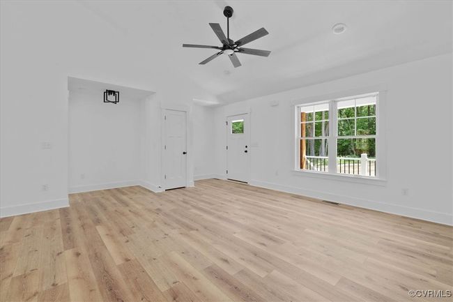 Unfurnished living room with lofted ceiling, baseboards, light wood finished floors, ceiling fan, and visible vents | Image 7