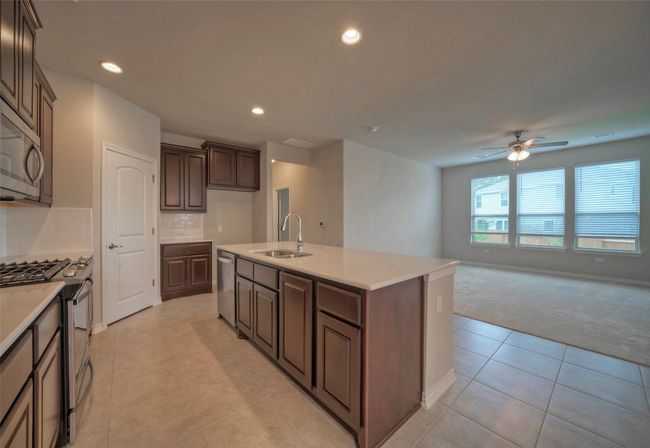 Kitchen featuring tasteful backsplash, a center island with sink, a sink, ceiling fan, and appliances with stainless steel finishes | Image 9