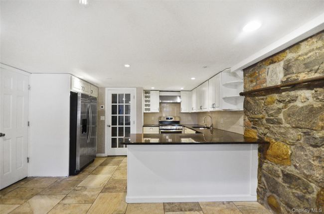Kitchen featuring open shelves, a peninsula, tasteful backsplash, dark stone counters, and recessed lighting | Image 7