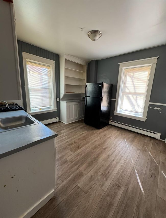 Kitchen with wood finished floors, baseboard heating, freestanding refrigerator, and a sink | Image 8