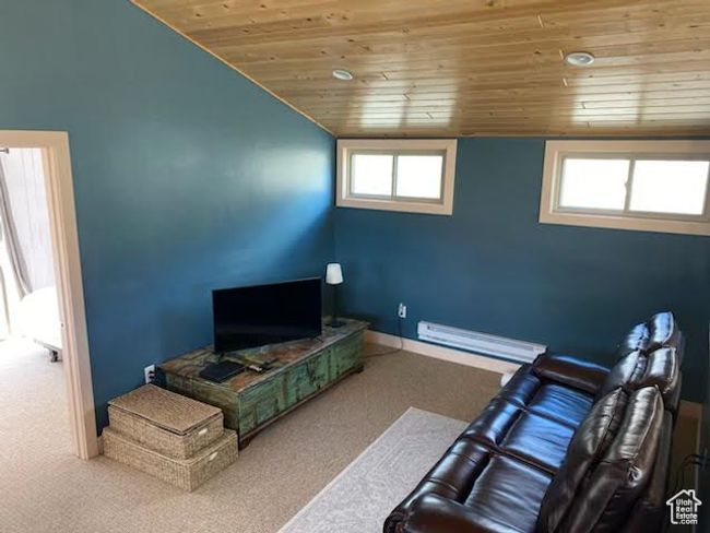 Carpeted living area with wood ceiling, a baseboard heating unit, vaulted ceiling, and baseboards | Image 4