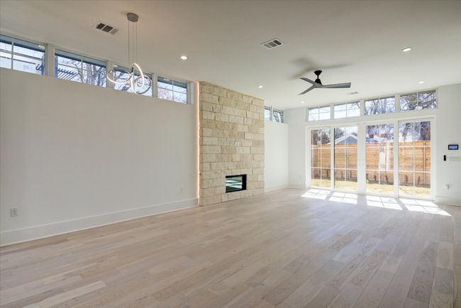 The open concept living/dining room features a limestone gas fireplace (backlit by LED lighting) and sliding glass doors that open to the 2nd of 2 yard areas. 10 foot ceilings and tons of windows make this a light, bright and airy space. Beautiful white oak flooring throughout. | Image 11