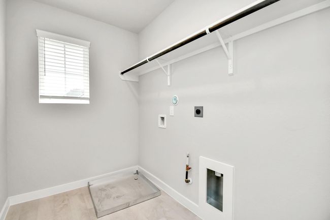 A spacious utility room with ample shelving for organization. It features connections for both gas and electric dryers, making it versatile and functional for all laundry needs. | Image 32