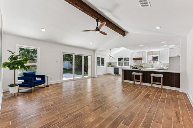 Exposed beams and expansive windows flood the living area with natural light. | Image 5