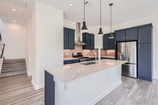 The beautiful kitchen features a spacious quartz island, perfect for barstools, complemented by elegant navy blue cabinets. | Image 21