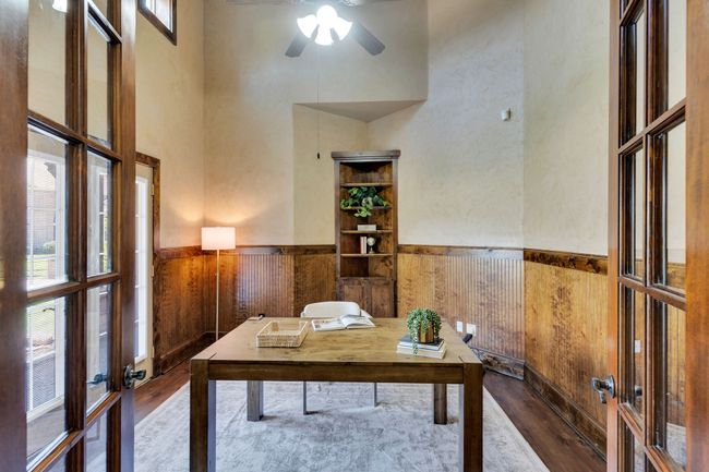 Office area with wood finished floors, french doors, a high ceiling, wainscoting, and a ceiling fan | Image 12