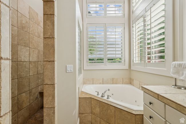 Full bathroom featuring plenty of natural light, a jetted tub, vanity, and tiled shower | Image 32