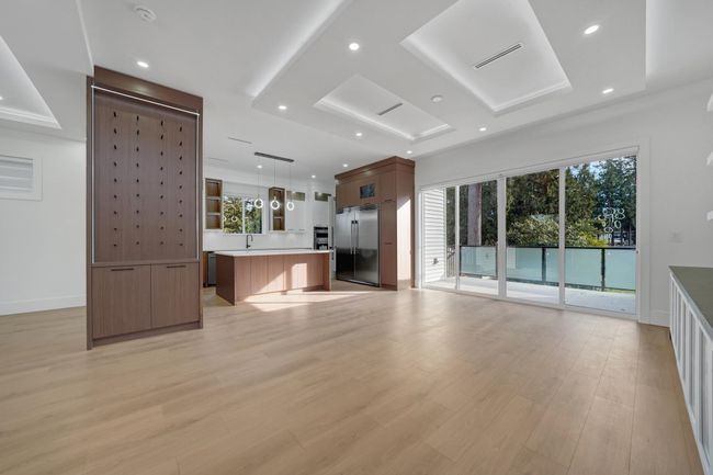 Unfurnished living room with light wood-style flooring, a tray ceiling, recessed lighting, baseboards, and a sink | Image 8