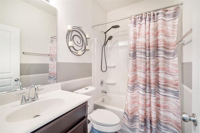 This stylish bathroom features a modern sink vanity, a sleek toilet, and a convenient shower/tub combo, offering both functionality and comfort. | Image 8
