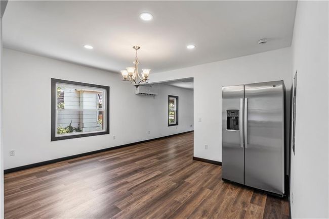 Kitchen featuring stainless steel fridge with ice dispenser, a chandelier, a wall mounted air conditioner, dark wood-type flooring, and recessed lighting | Image 24