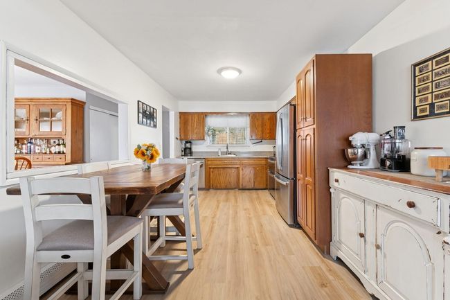 Kitchen with brown cabinetry, light wood-style flooring, a sink, light countertops, and stainless steel appliances | Image 7