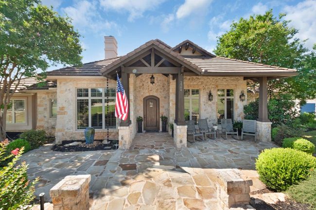 View of front of home with stone siding, a tiled roof, a chimney, and a patio | Image 4