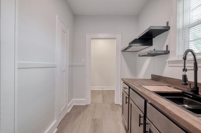 Kitchen with butcher block countertops, light wood-style floors, open shelves, and range hood | Image 32
