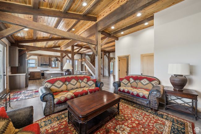 Living room with wooden ceiling, wood finished floors, vaulted ceiling with beams, stairs, and recessed lighting | Image 38