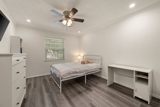 Bedroom featuring dark wood-type flooring, a textured ceiling, crown molding, and recessed lighting | Image 17