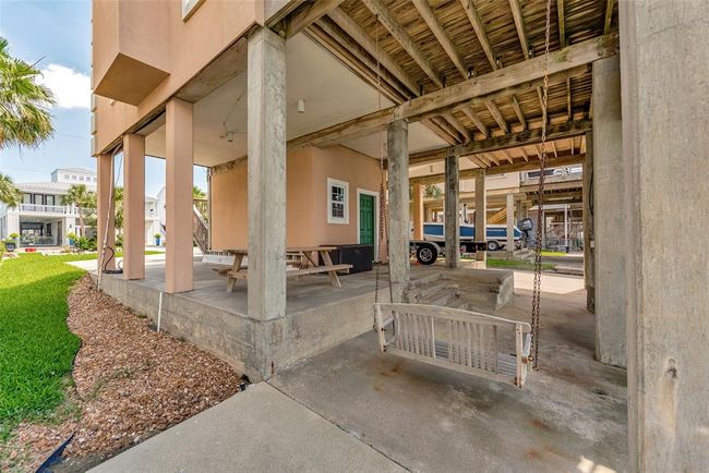 The ground level includes a covered deck with a porch swing and picnic table, plus a carport with space for parking and storage. | Image 33