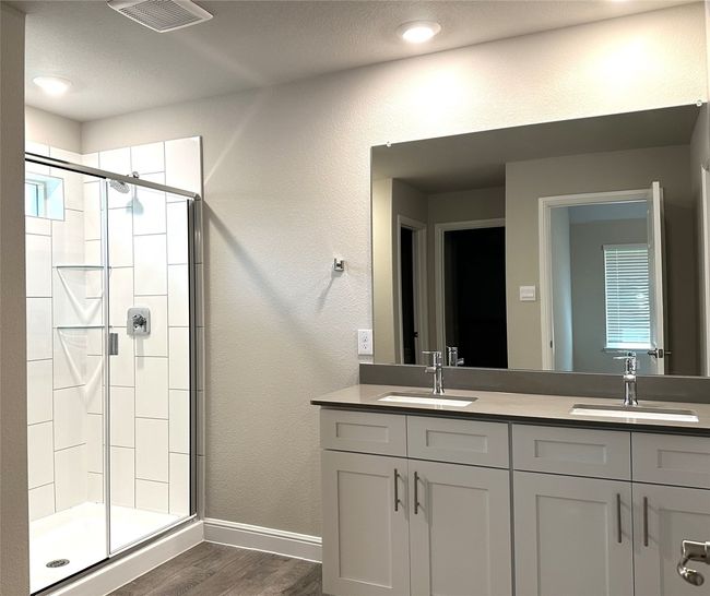 Bathroom featuring wood finished floors, a shower stall, and double vanity | Image 9