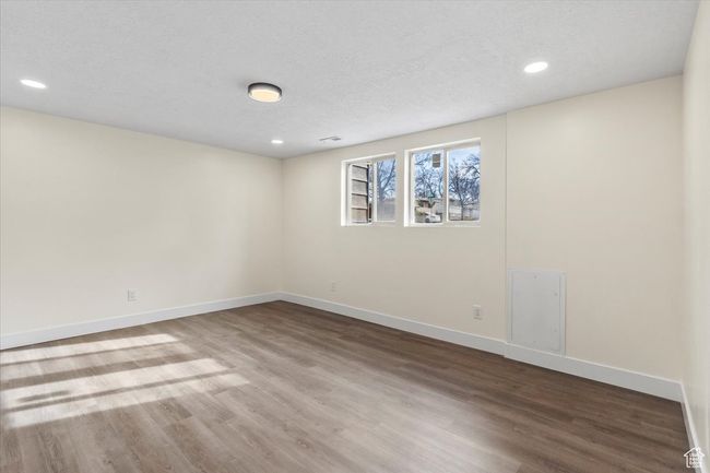 Empty room featuring wood finished floors, a textured ceiling, baseboards, visible vents, and recessed lighting | Image 13