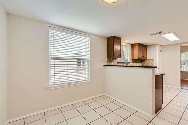 Kitchen with backsplash, dark countertops, visible vents, and light tile patterned floors | Image 11