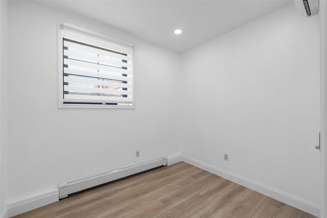 Unfurnished room with a baseboard heating unit, light wood-type flooring, baseboards, and recessed lighting. | Image 7