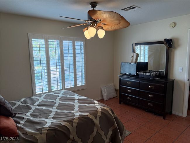 Bedroom with light tile patterned flooring, visible vents, a ceiling fan, and multiple windows | Image 6