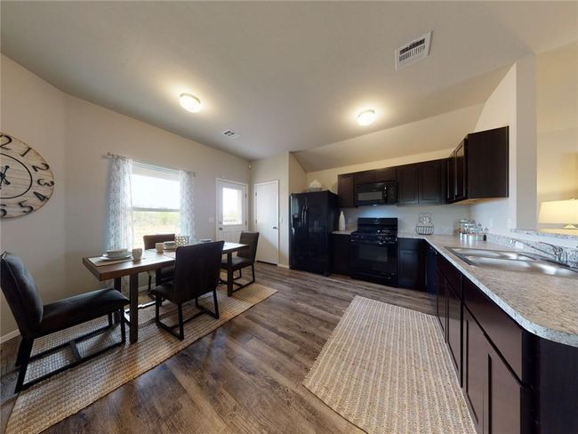 Kitchen featuring black appliances, sink, dark brown cabinets, and dark wood-type flooring | Image 9