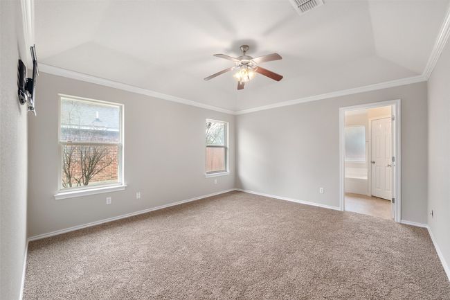Bedroom with crown molding, light colored carpet, baseboards, and ceiling fan | Image 10