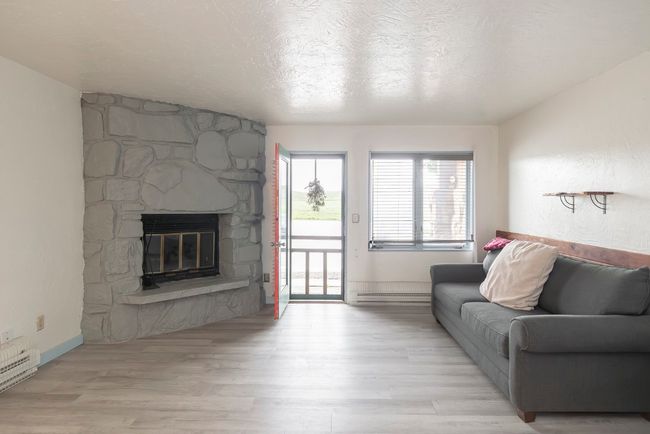 Living area featuring light wood-style floors, a fireplace, and a textured ceiling | Image 14