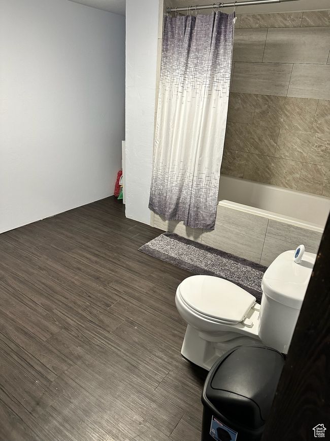Bathroom featuring hardwood / wood-style flooring, toilet, and shower / bath combo with shower curtain | Image 24