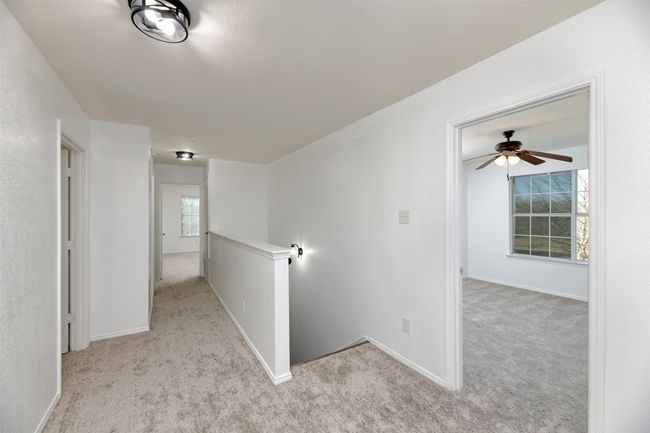 Hallway featuring an upstairs landing, light colored NEW carpet, and baseboards | Image 19
