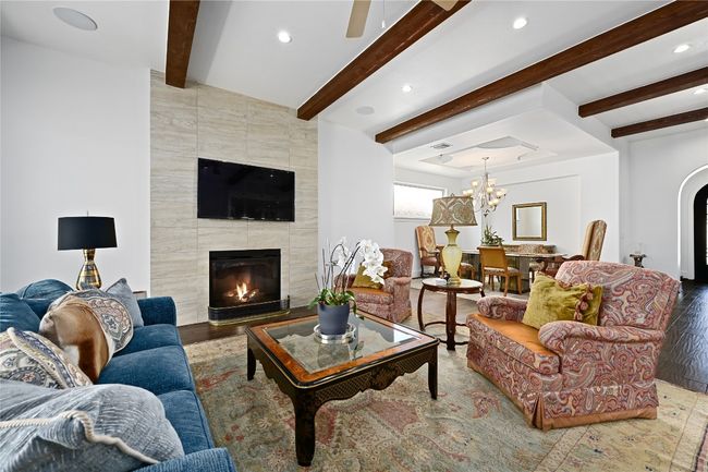Living area featuring a tile fireplace, beam ceiling, recessed lighting, wood floors | Image 5