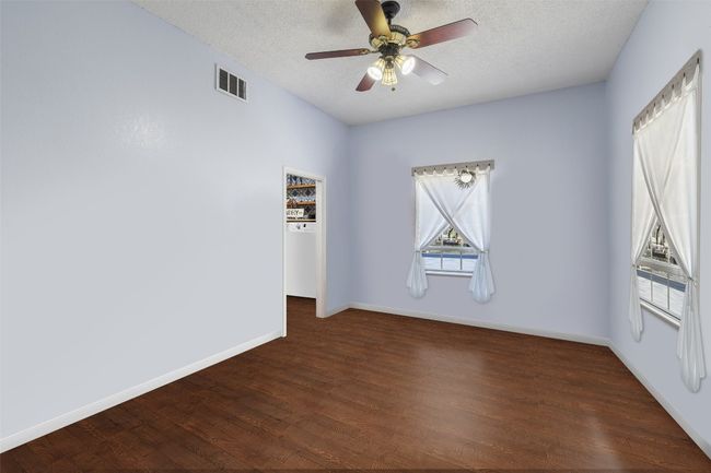 Unfurnished room featuring dark wood-style flooring, baseboards, a textured ceiling, and a ceiling fan | Image 25