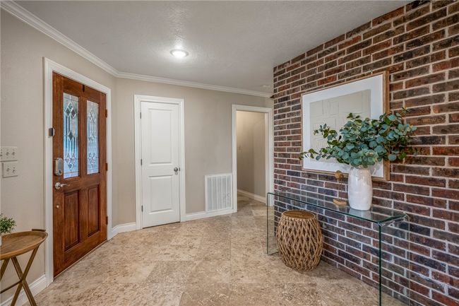 Entryway with baseboards, visible vents, brick wall, a textured ceiling, and crown molding | Image 10