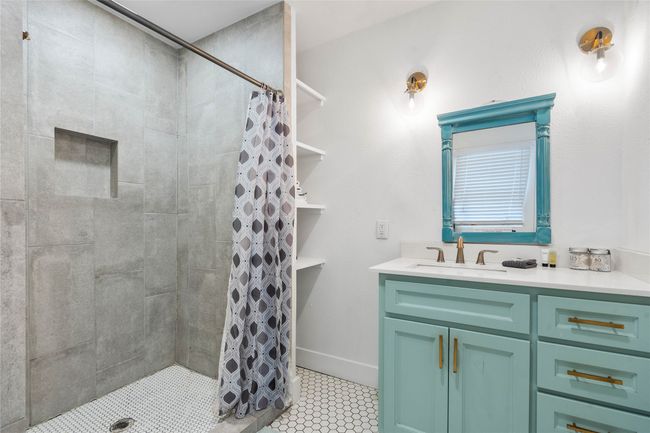 Bathroom with a tile shower, vanity, and tile patterned flooring | Image 19