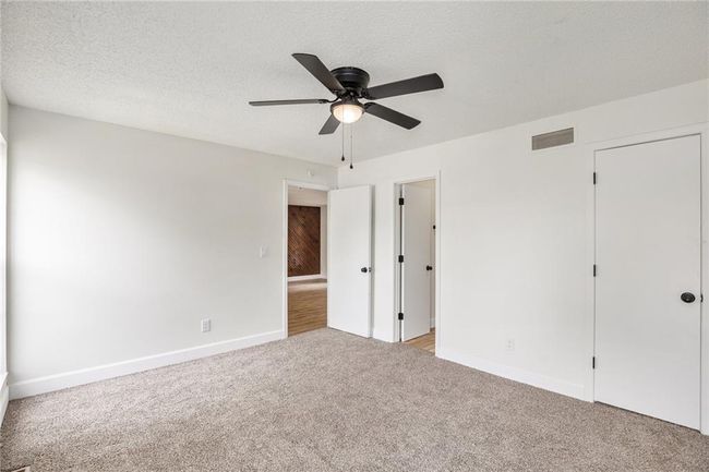 Unfurnished bedroom featuring light colored carpet, baseboards, and ceiling fan | Image 12